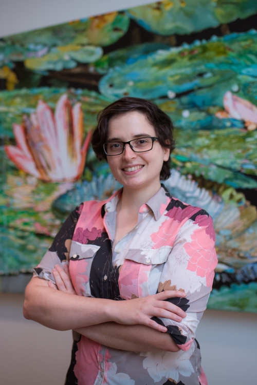 Rebecca Povilus stands in front of a painting of water lilies