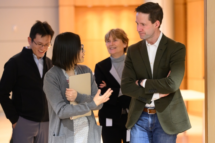 Na Sun and Michael Chambers walk and talk, with Ruth Lehmann and another person in the background