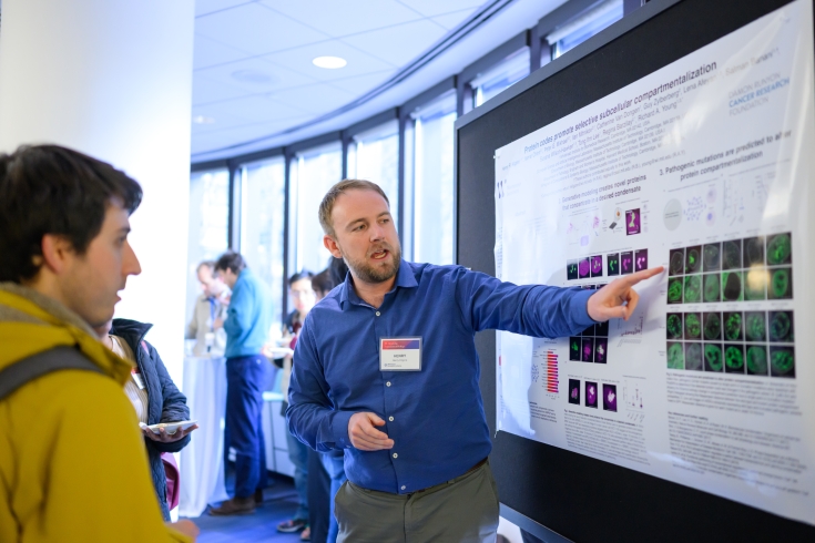 A person points at their poster and explains it to someone else