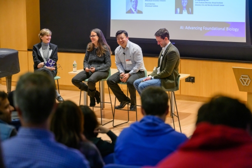Three panelists and Ruth Lehmann chatting, sitting on stools in front of an audience